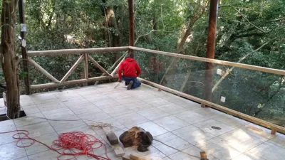 Tiled deck and glass balustrade panels amid dense jungle backdrop.
