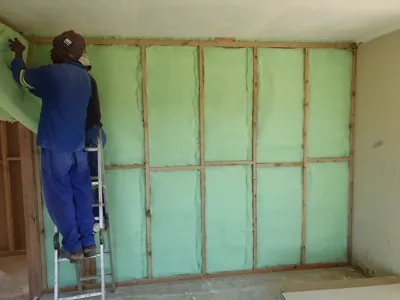 Fitting green nutec insulation panels between timber studs before installing drywall